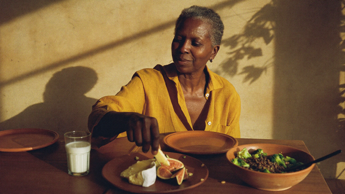 Woman in her 60s enjoying a lunch of cheese, figs and lentil salad in warm afternoon light