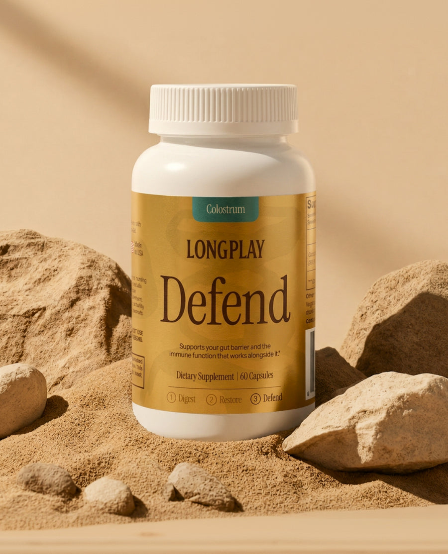Longplay Defend colostrum bottle on pale sand with scattered rocks